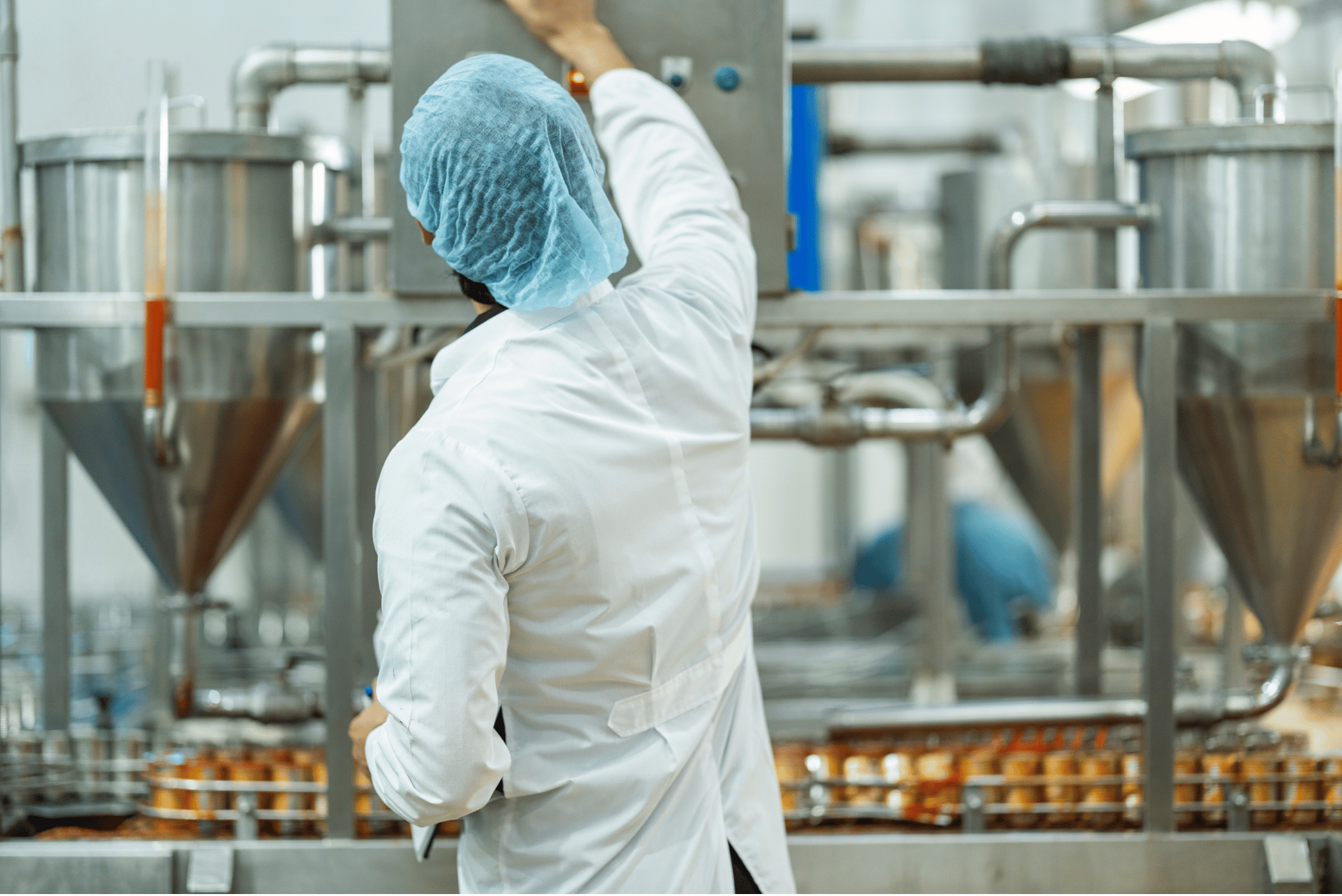 Food manufacturer wearing a hair cap working with machinery.