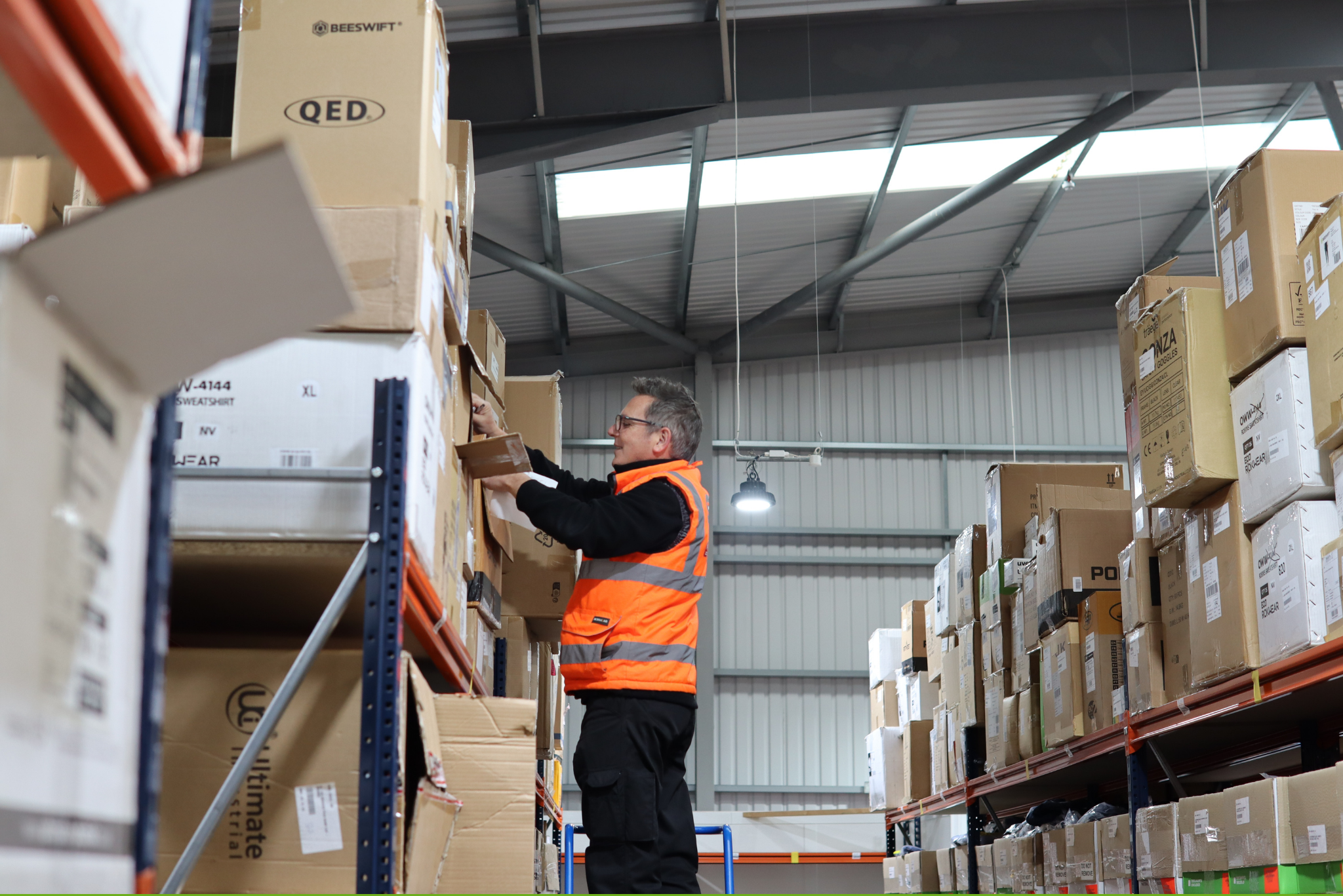 Worker stacking boxes on a warehouse shelf.