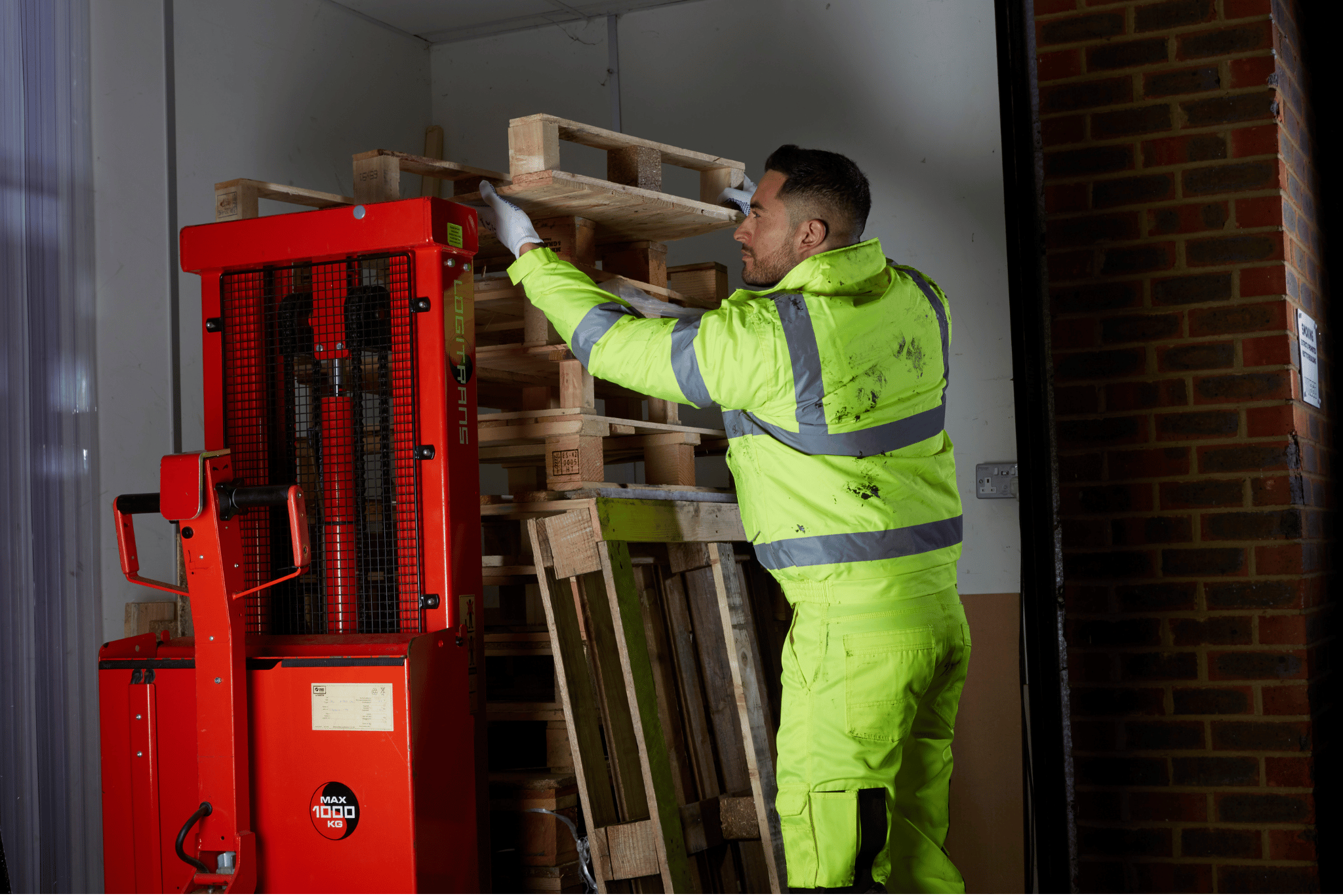 Logistics worker moving pallets wearing hi-vis.