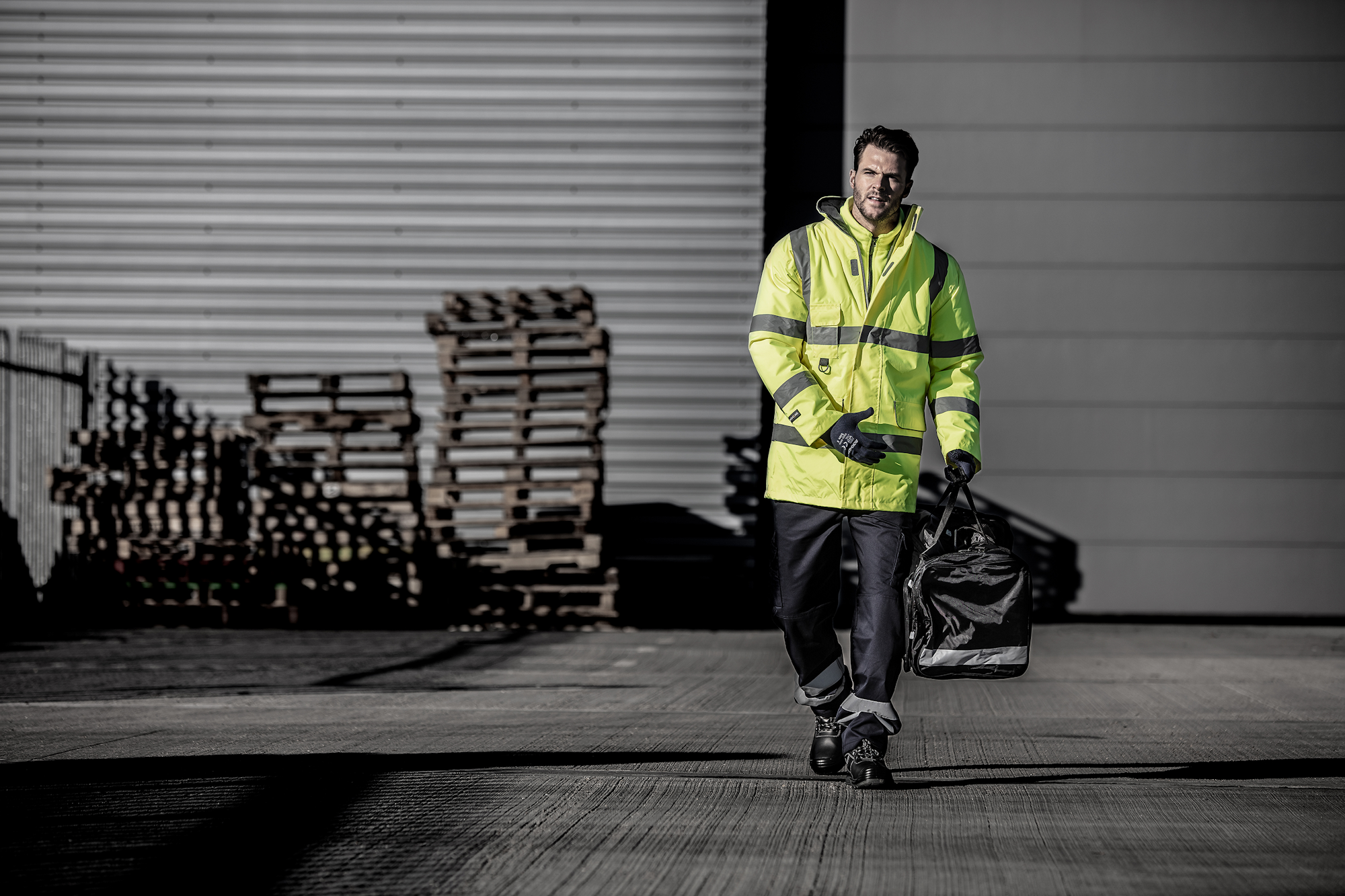 Employee walking in full safety workwear holding a PPE bag