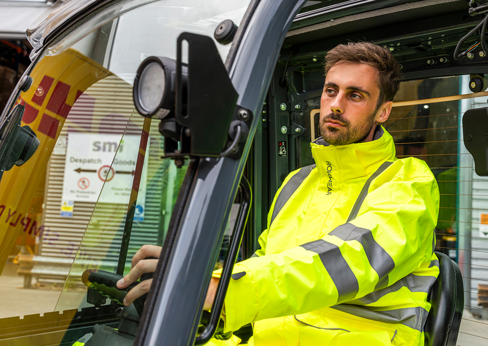 Worker operating a forklift wearing uniform.