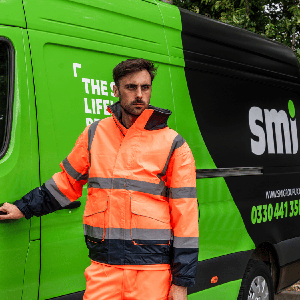 Man in hi-vis orange workwear in front of a delivery van.